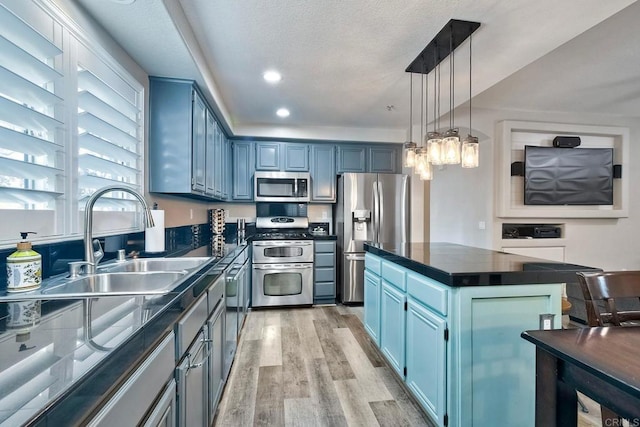 kitchen featuring blue cabinets, sink, decorative light fixtures, a center island, and stainless steel appliances