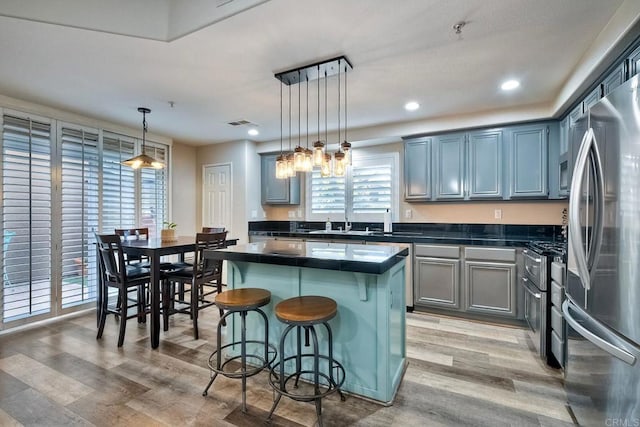 kitchen with a breakfast bar, decorative light fixtures, hardwood / wood-style flooring, a center island, and stainless steel appliances