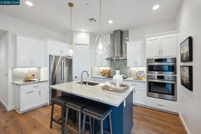 kitchen featuring white cabinetry, sink, tasteful backsplash, and wall chimney range hood