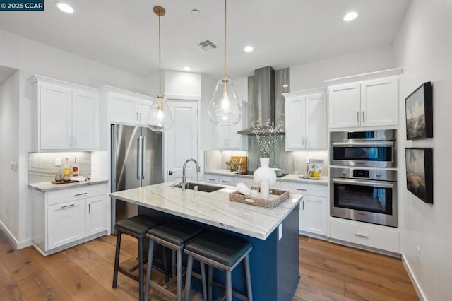 kitchen featuring tasteful backsplash, white cabinets, wall chimney exhaust hood, and sink