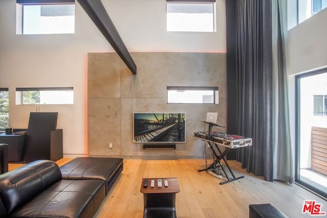 living room featuring light wood-type flooring, a towering ceiling, and plenty of natural light