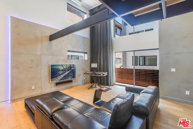 living room with light hardwood / wood-style floors and a towering ceiling