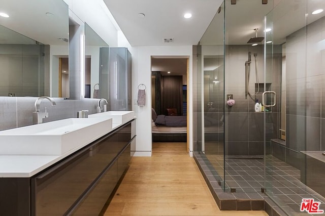 bathroom featuring a shower with door, backsplash, hardwood / wood-style flooring, and vanity