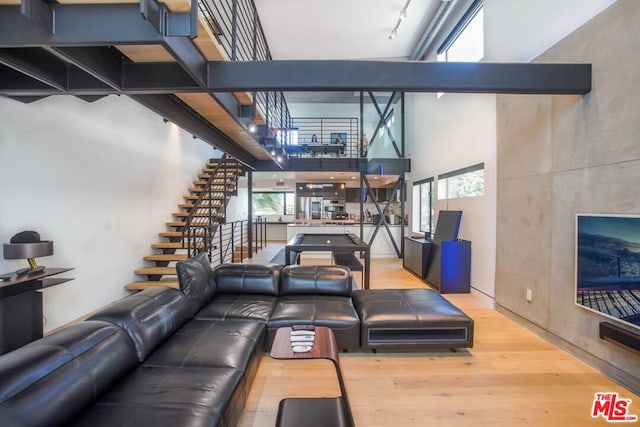 living room featuring hardwood / wood-style flooring, track lighting, and a towering ceiling