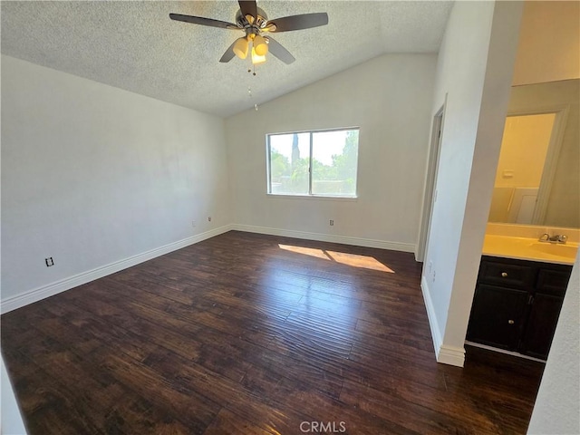 empty room featuring lofted ceiling, ceiling fan, dark hardwood / wood-style floors, and a textured ceiling