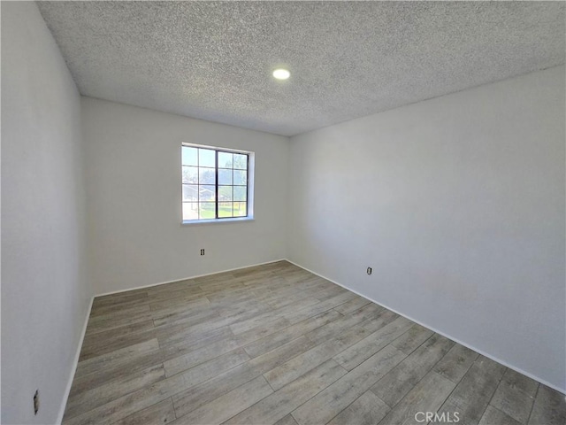 empty room featuring a textured ceiling and wood-type flooring