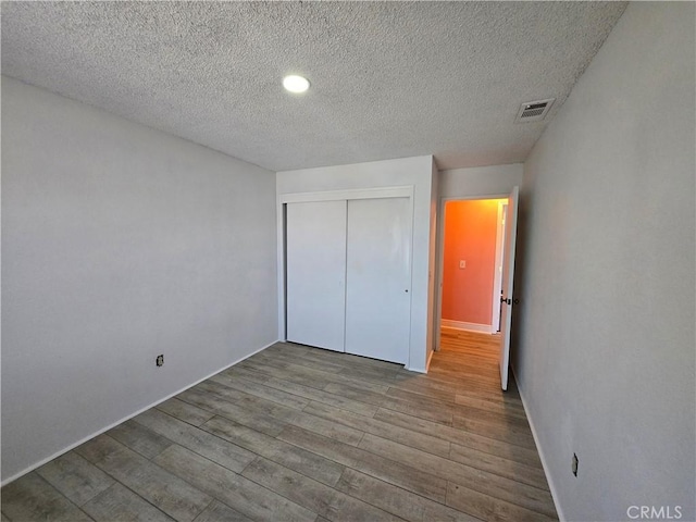 unfurnished bedroom with a closet, a textured ceiling, and hardwood / wood-style flooring