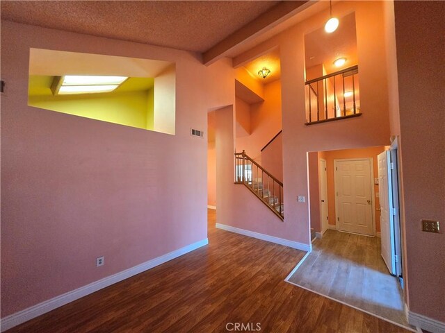 entryway with hardwood / wood-style flooring, a textured ceiling, and vaulted ceiling with beams