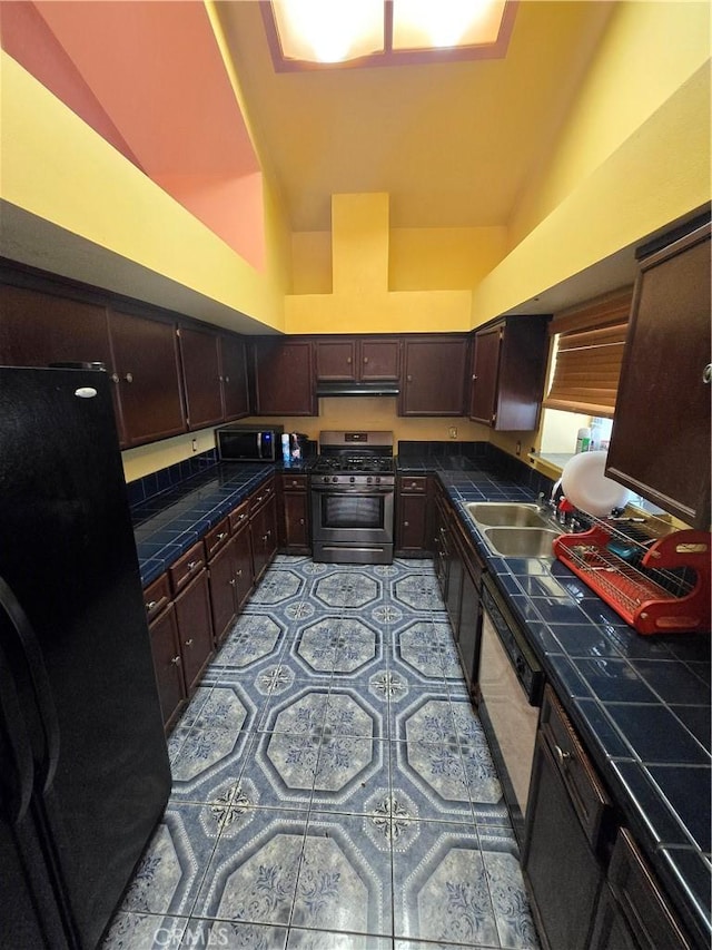 kitchen featuring appliances with stainless steel finishes, tile countertops, dark brown cabinetry, and sink