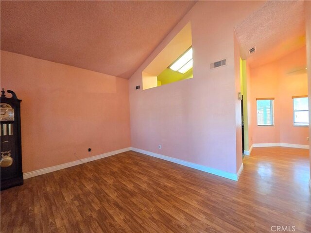 spare room with hardwood / wood-style flooring, a textured ceiling, and high vaulted ceiling