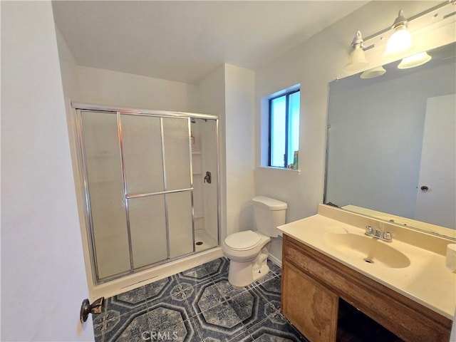 bathroom featuring a shower with shower door, vanity, tile patterned flooring, and toilet