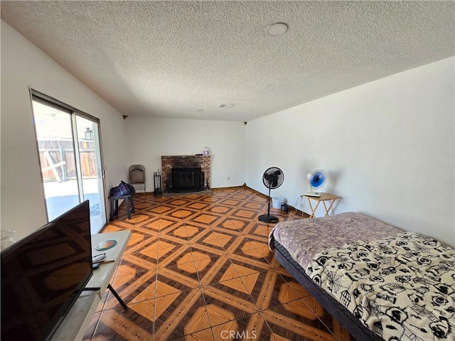 bedroom with access to outside, a brick fireplace, and a textured ceiling