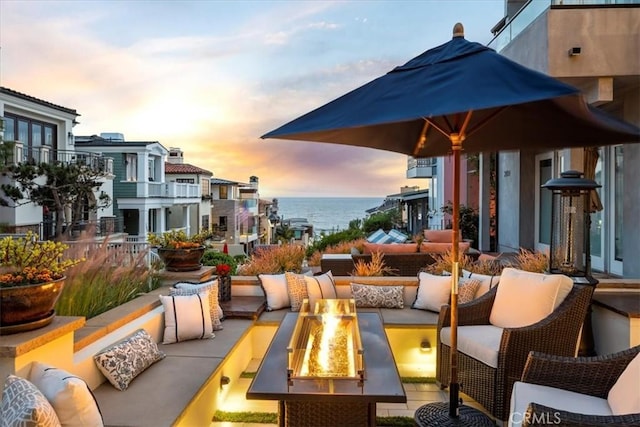 patio terrace at dusk featuring an outdoor living space with a fire pit and a water view