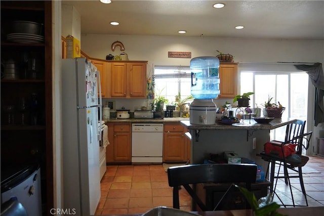 kitchen with light tile patterned floors, white appliances, sink, and a healthy amount of sunlight