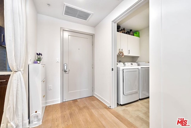 laundry room featuring light wood-type flooring, separate washer and dryer, and cabinets