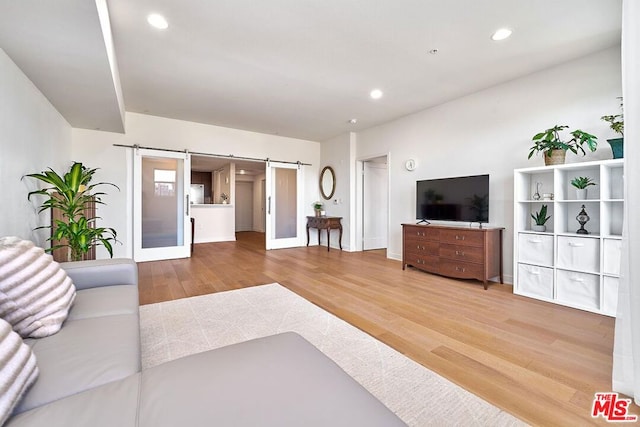 living room with french doors, a barn door, and hardwood / wood-style floors