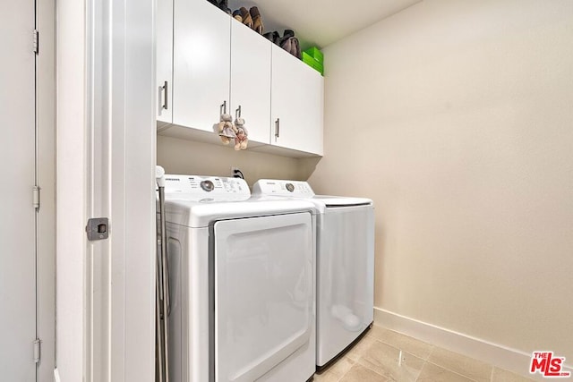 laundry room with light tile patterned floors, washer and dryer, and cabinets