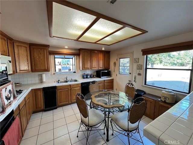 kitchen with a wealth of natural light, tasteful backsplash, tile counters, and sink