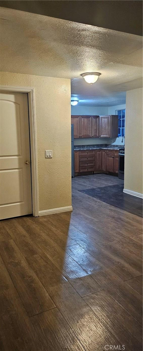 kitchen featuring dark hardwood / wood-style flooring, refrigerator, a textured ceiling, and black electric range