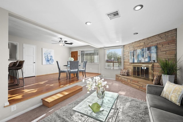 living room featuring a brick fireplace, carpet floors, and ceiling fan