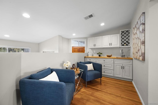 sitting room featuring wet bar and light wood-type flooring