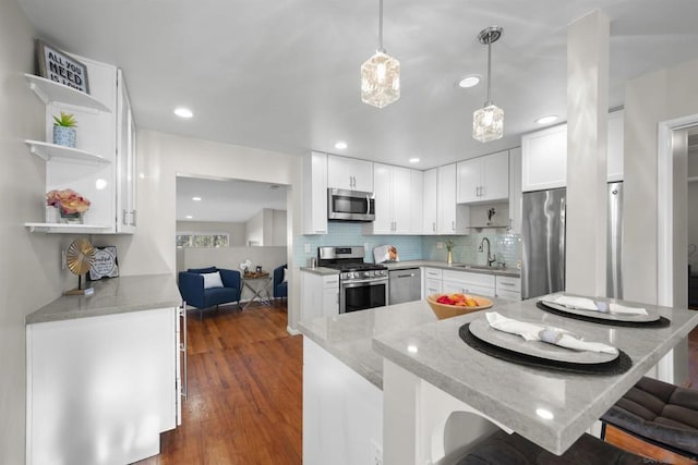 kitchen with stainless steel appliances, a kitchen breakfast bar, white cabinets, decorative light fixtures, and kitchen peninsula