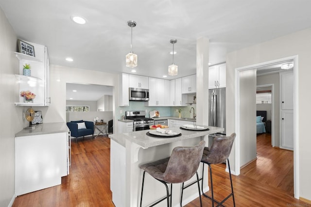 kitchen featuring appliances with stainless steel finishes, dark wood-type flooring, white cabinets, and decorative light fixtures