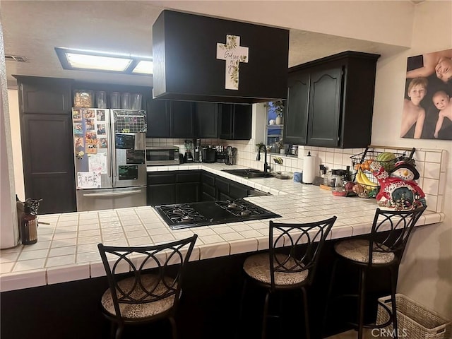 kitchen with tile countertops, stainless steel appliances, and sink