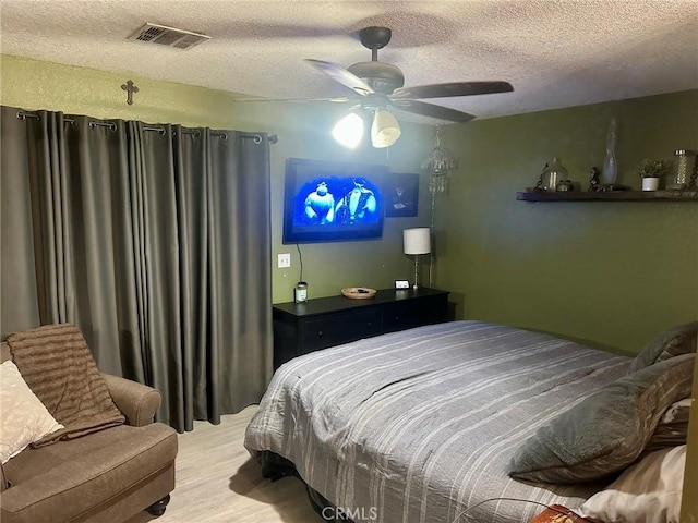 bedroom featuring ceiling fan, light hardwood / wood-style floors, and a textured ceiling