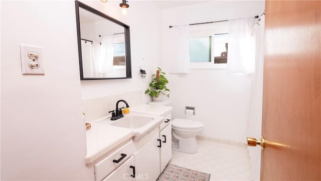 bathroom with toilet, vanity, and tile patterned flooring