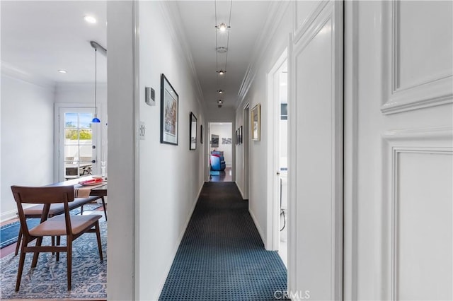 hall with dark colored carpet and crown molding