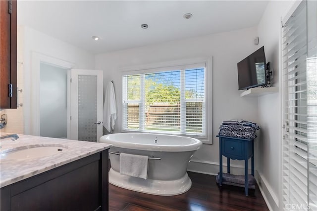 bathroom with hardwood / wood-style flooring, plenty of natural light, a bathtub, and vanity