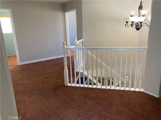 hall featuring carpet and a notable chandelier