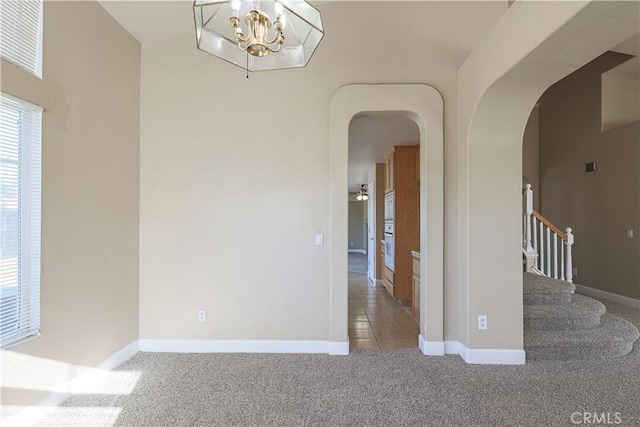 carpeted empty room featuring a chandelier