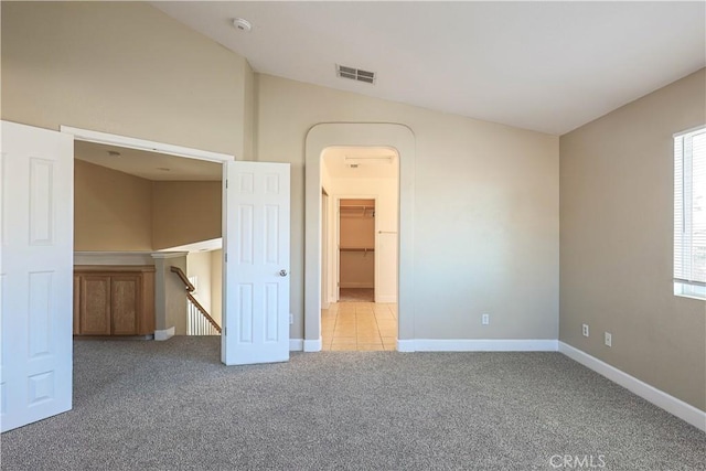 unfurnished bedroom with a walk in closet and light colored carpet