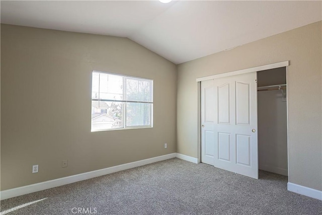 unfurnished bedroom with vaulted ceiling, a closet, and carpet flooring