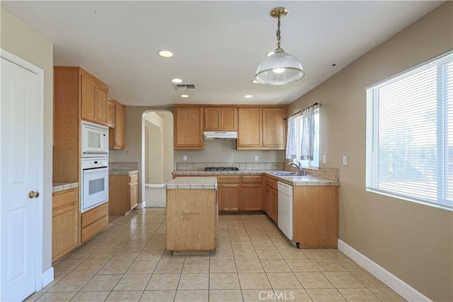 kitchen featuring decorative light fixtures, light tile patterned flooring, white appliances, and a center island