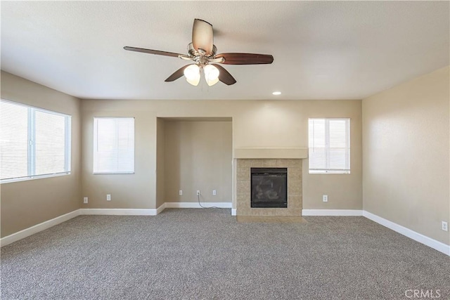 unfurnished living room featuring ceiling fan, carpet flooring, and a tiled fireplace