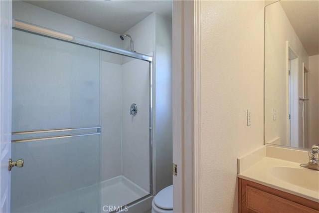 bathroom with toilet, vanity, and a shower with door