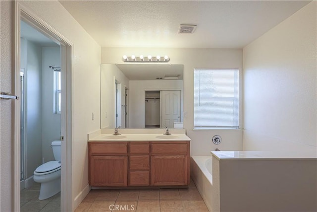 bathroom featuring tile patterned floors, toilet, vanity, and a bath