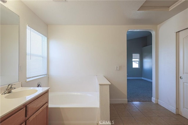 bathroom with tile patterned floors, a healthy amount of sunlight, a bathtub, and vanity