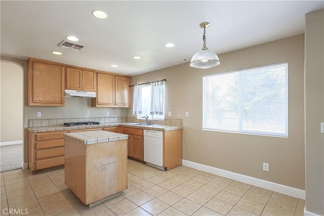 kitchen with pendant lighting, a center island, white dishwasher, light tile patterned floors, and stainless steel gas stovetop