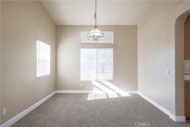 carpeted spare room with a chandelier