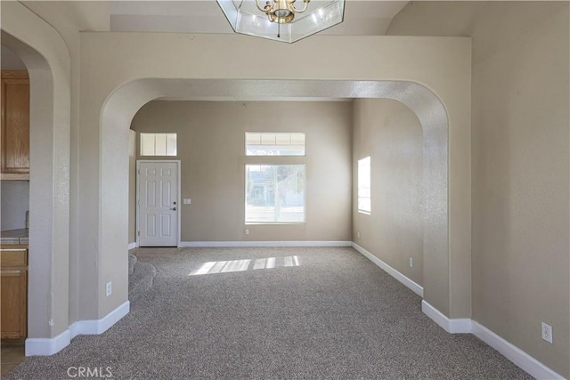 carpeted spare room with a notable chandelier