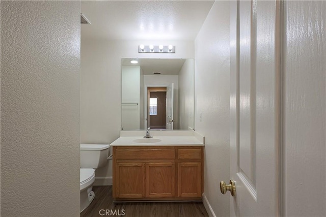 bathroom with toilet, wood-type flooring, and vanity