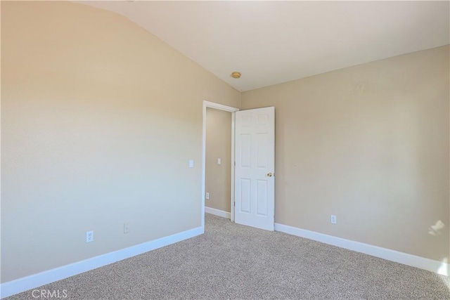 carpeted empty room featuring vaulted ceiling