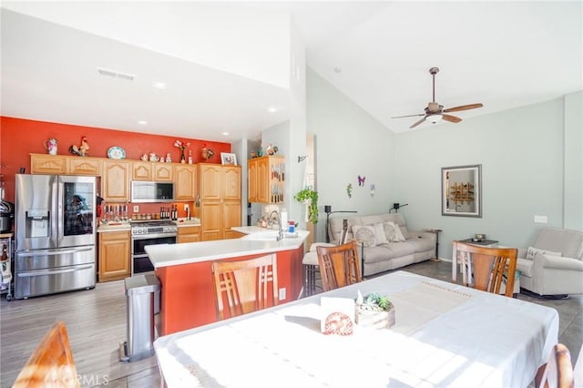 dining space with light wood-type flooring, ceiling fan, lofted ceiling, and sink