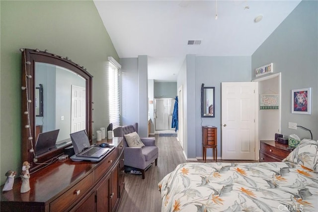 bedroom featuring ensuite bath, lofted ceiling, and light hardwood / wood-style floors