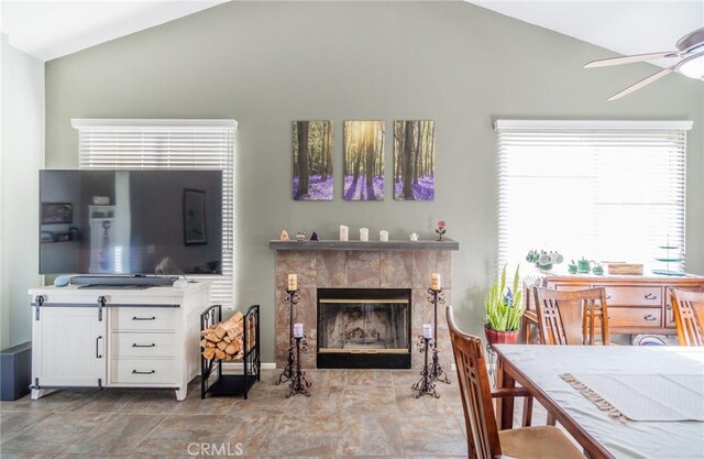 living room featuring ceiling fan, lofted ceiling, and a tiled fireplace