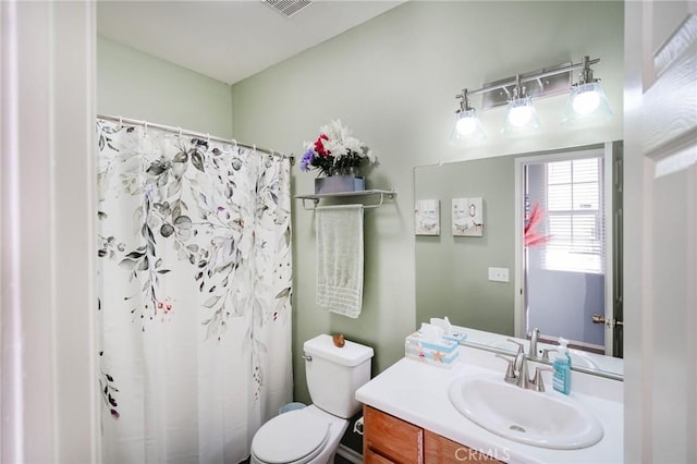 bathroom featuring toilet, vanity, and curtained shower